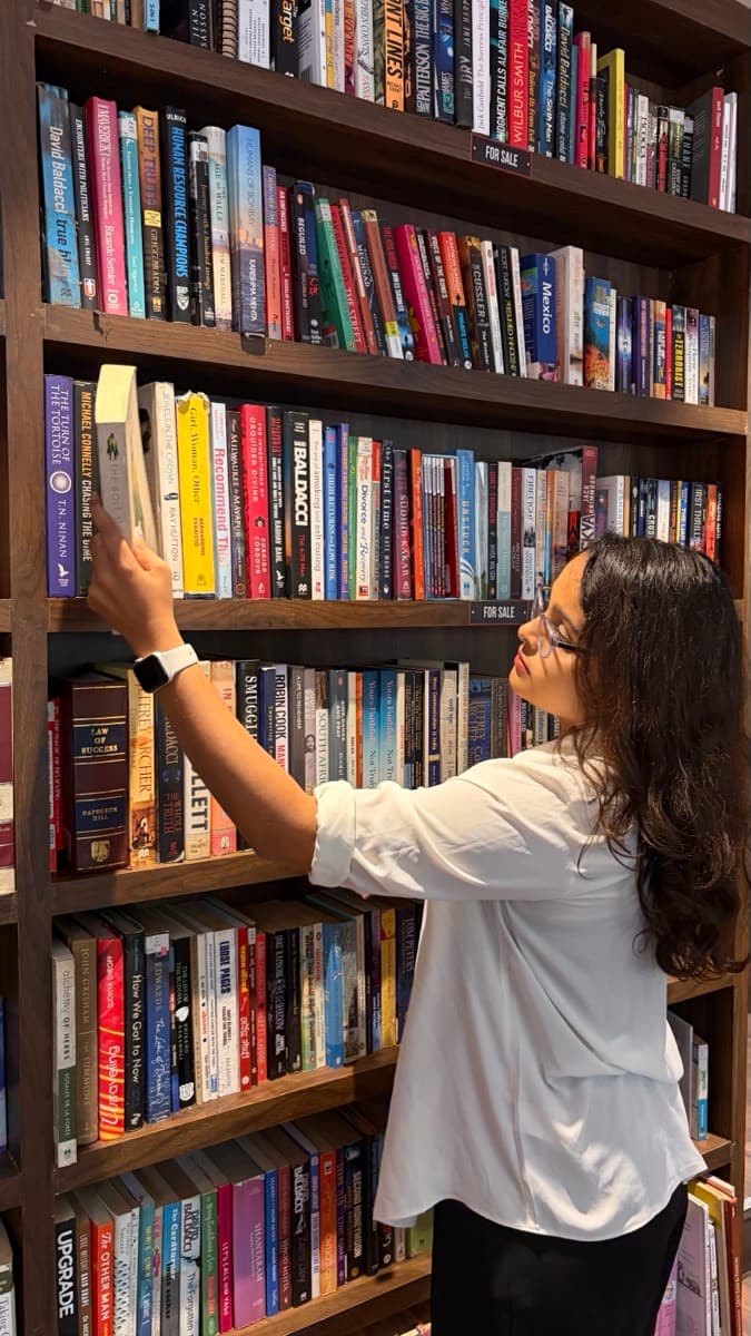 Aditi picking a book off a shelf